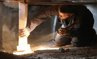 A professional inspecting wooden beams under the floor of a structure in Birmingham, AL