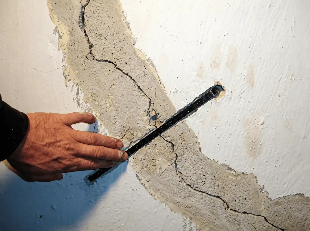 A wall with a large crack is being inspected by a professional in Birmingham, AL