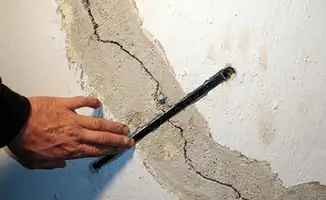 A wall with a large crack is being inspected by a professional in Birmingham, AL
